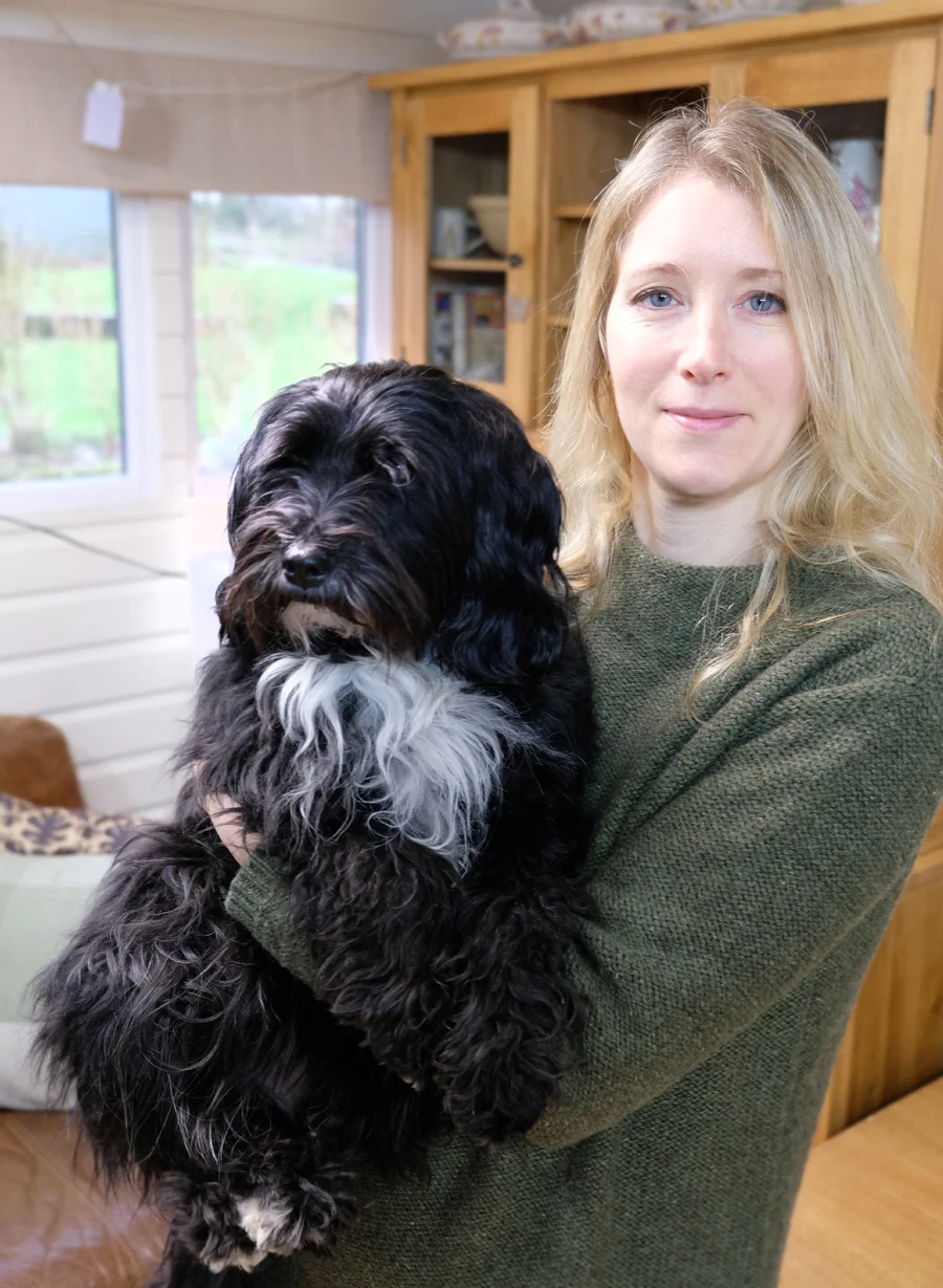 Melanie Phillips, a smiling female artist, stands next to an easel.