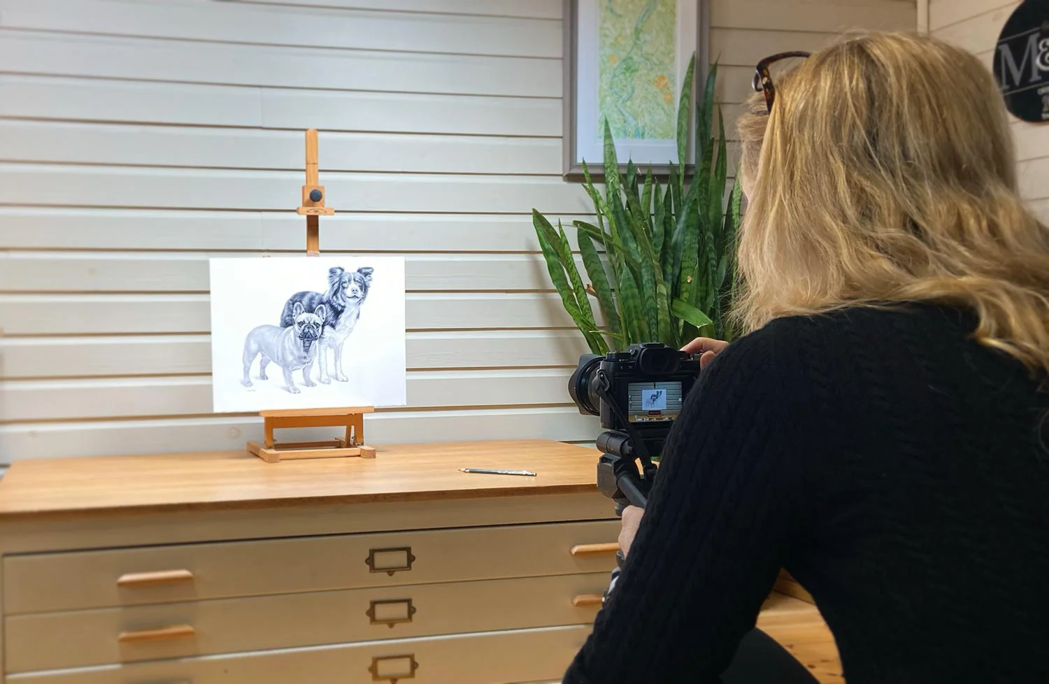 Melanie photographing a completed drawing on her plan chest, with studio lighting.