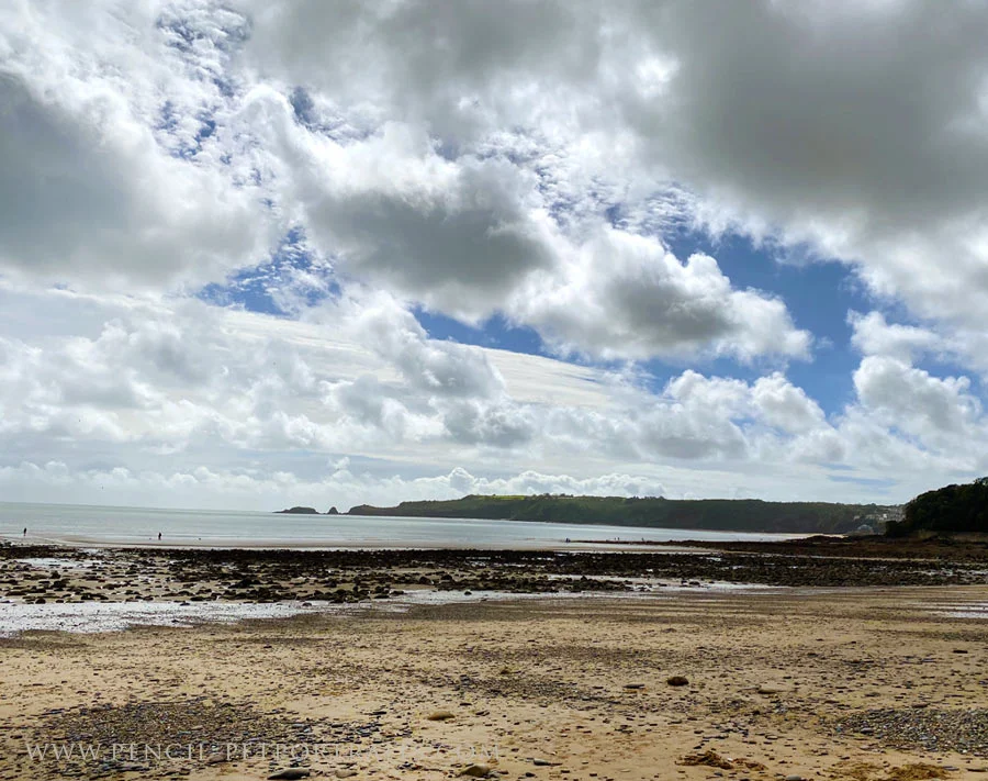 A serene sandy beach view in West Wales, with waves gently lapping.