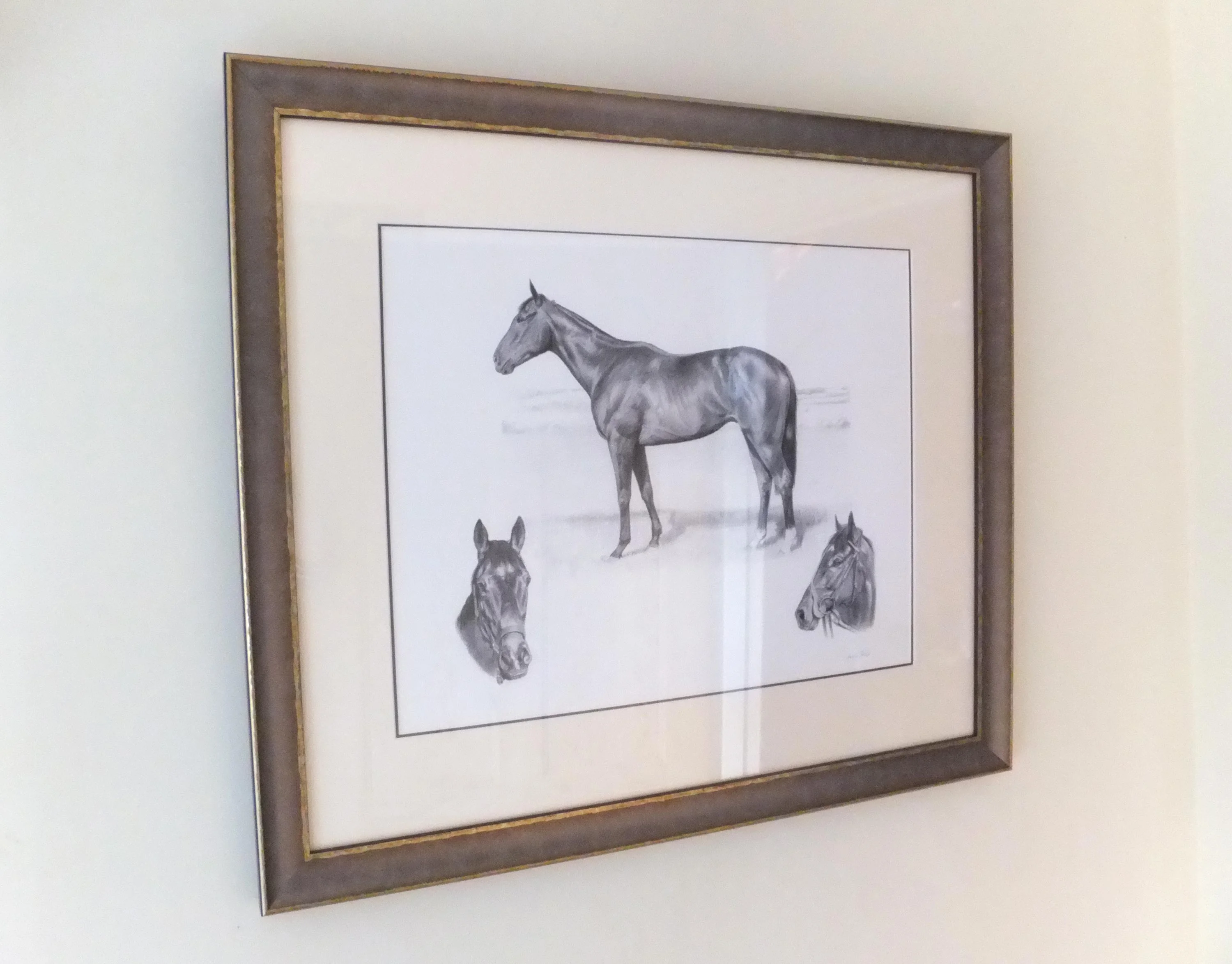 The framed original pencil portrait of racehorse Charles displayed in a home setting.