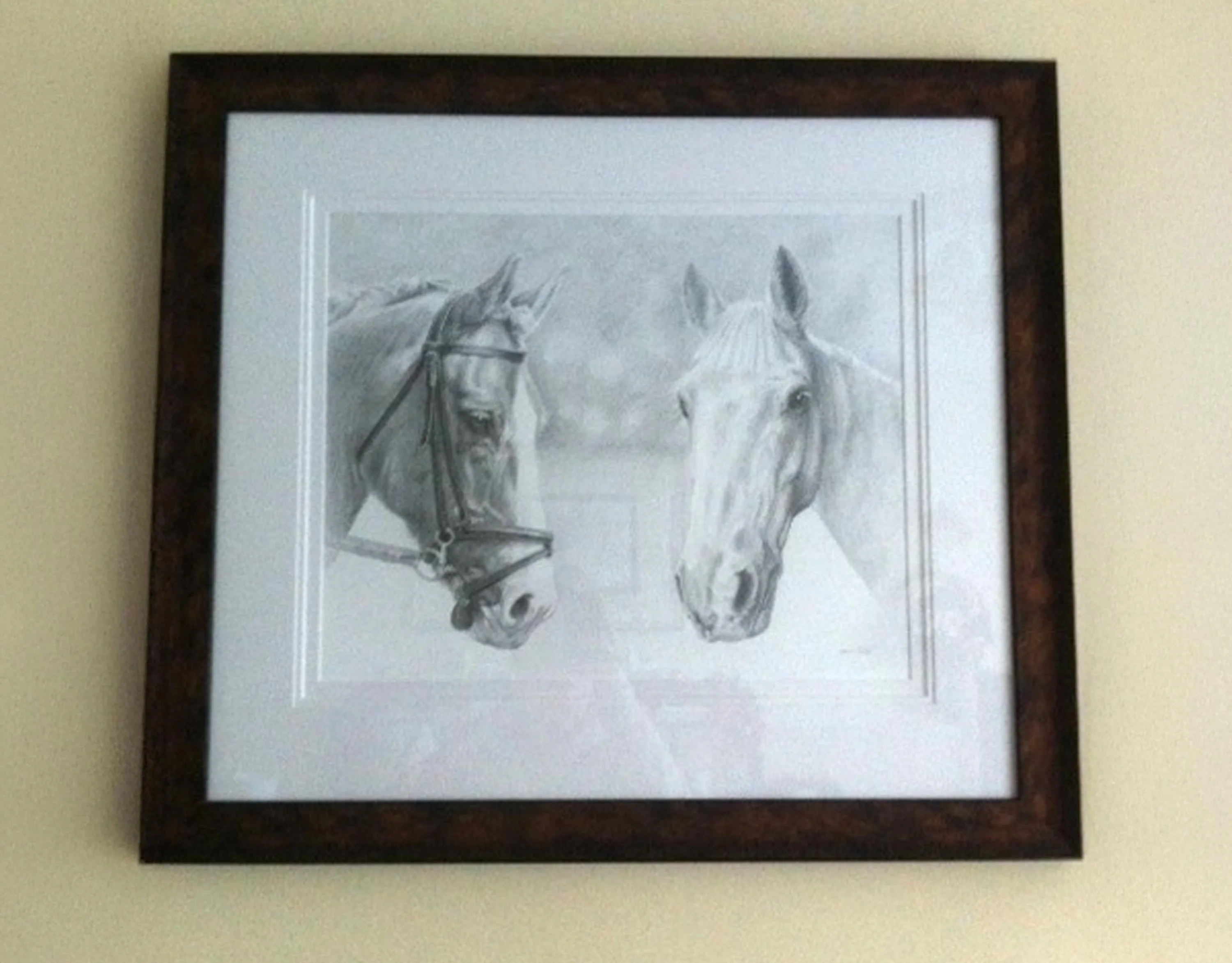 The framed pencil portrait of Monty and Duffy, two horses, hanging on a living room wall.